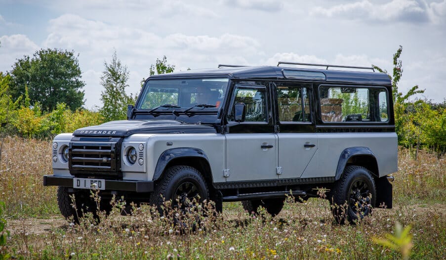 A land rover defender funeral hearse parked in a field